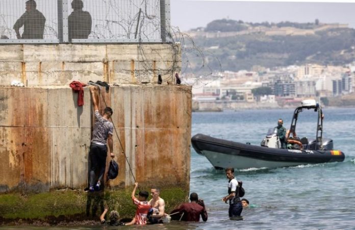 Des policiers espagnoles tentent de disperser des migrants qui arrivent à l'enclave espagnole de Ceuta, le 18 mai 2021 à Fnideq afp.com - FADEL SENNA